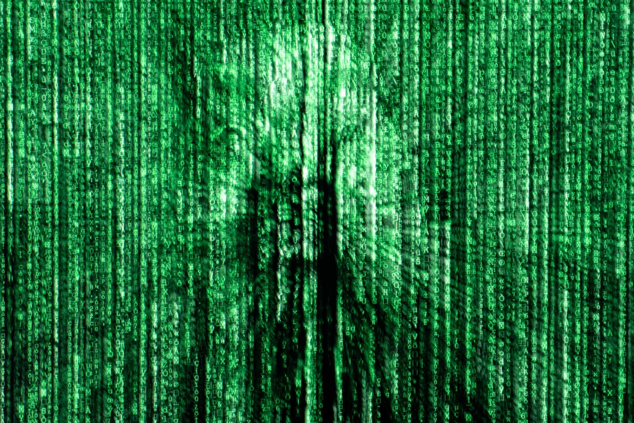 grüne herabfallende Codezeichen mit schemenhafter Figur im Hintergrund