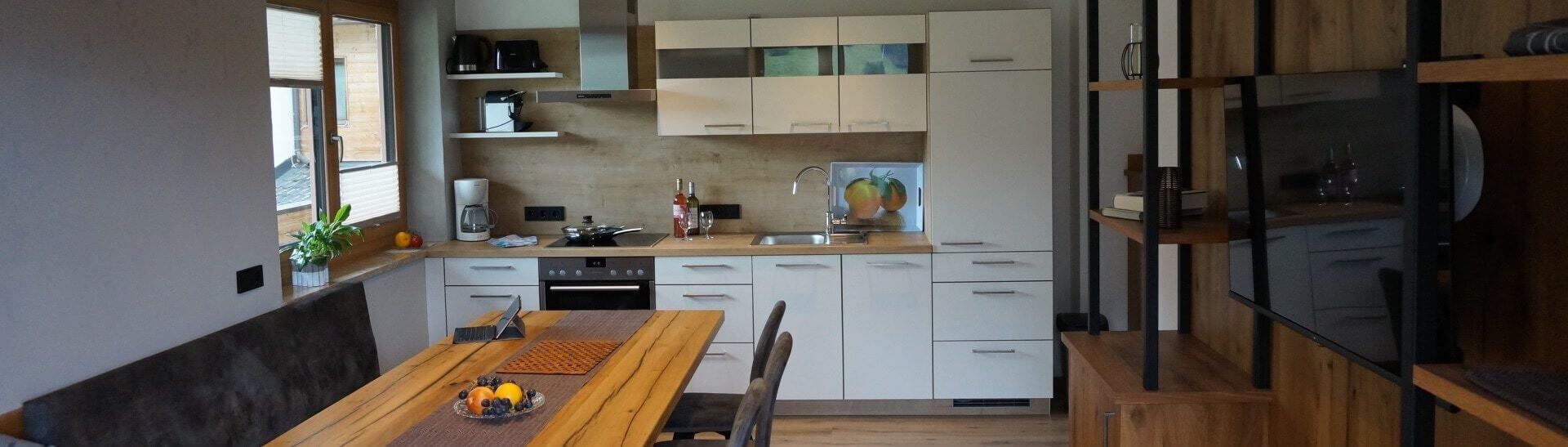 Moderne Küche im alpenländischen Stil mit Esstisch und Holzdekor in Appartement Saalbach