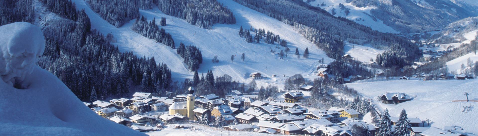 Verschneite Alpenlandschaft mit Dorf Saalbach und Bergpanorama im Winter
