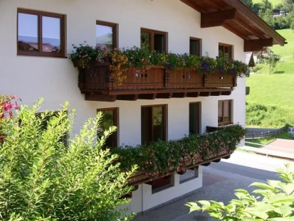 Gemütliches Haus Babsy in Zell am See mit Balkon und blühenden Pflanzen, umgeben von Natur.