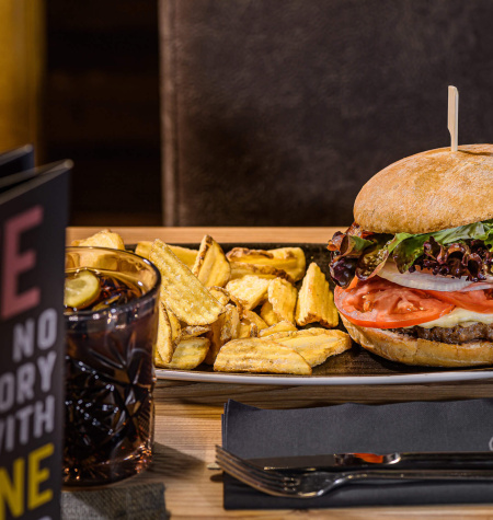 Saftiger Burger mit frischem Gemüse und knusprigen Pommes auf einem Teller im Restaurant.