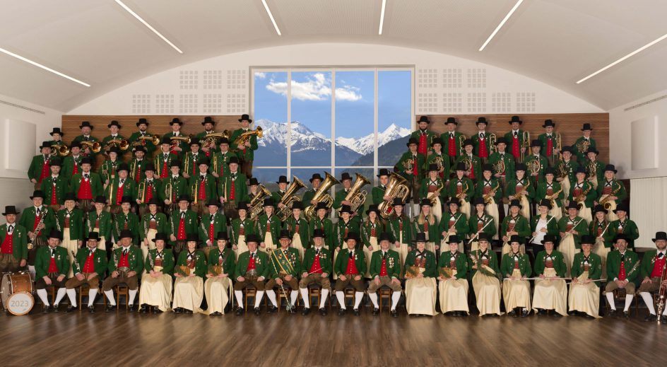 Gruppenfoto des Pinzgauer Blasmusikverbandes vor einem Bergpanorama in festlicher Tracht.