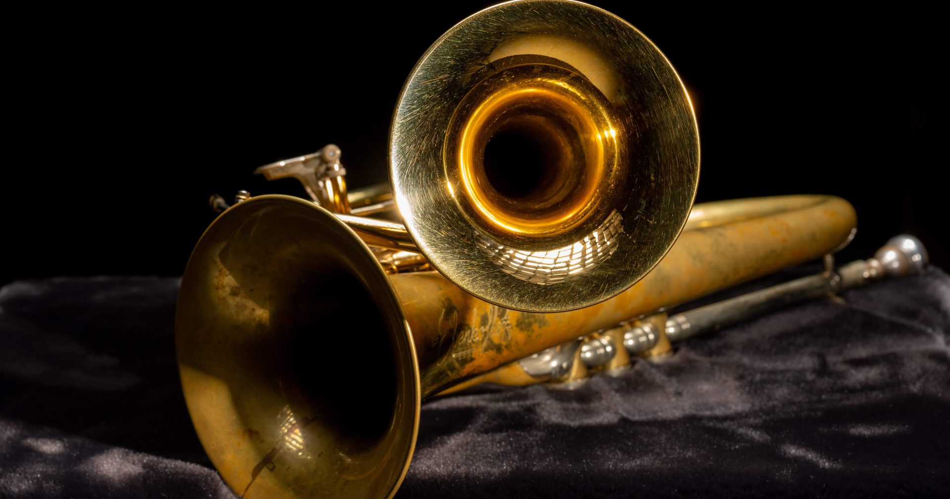 Goldene Trompete vor schwarzem Hintergrund, symbolisiert Blasmusik und musikalische Vielfalt.