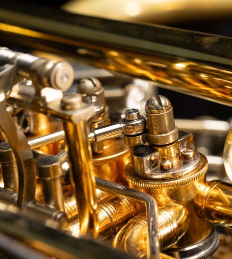 Detailaufnahme eines Blechblasinstruments mit glänzenden Ventilen und Rohrleitungen.