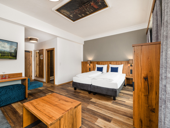 Modernes Doppelzimmer mit Holzmöbeln und gemütlicher Sitzecke im Hotel Mittersill