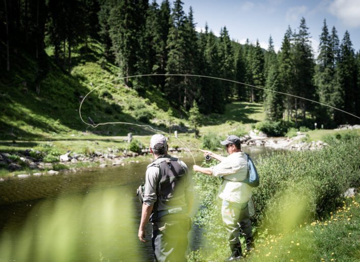 Zwei Männer beim Fliegenfischen an einem Gebirgsbach