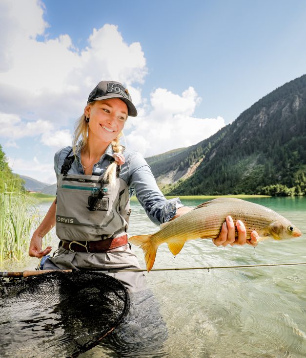 Frau beim Fliegenfischen in klarem Bergsee