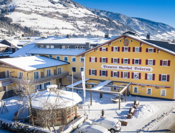 Gelbes Hotel Bräurup im Winter mit verschneiten Bergen