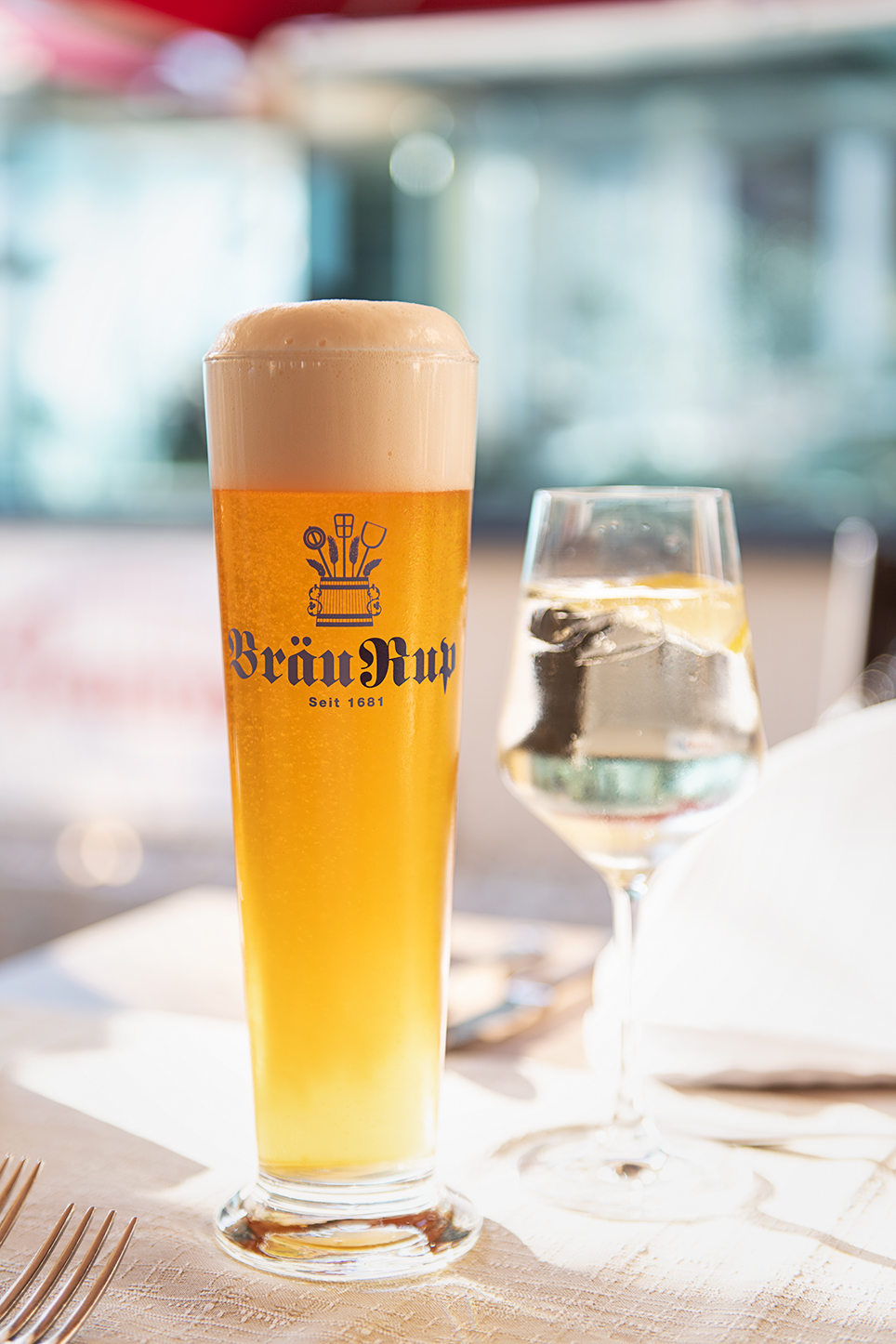 Bierglas und Weinglas auf gedecktem Tisch