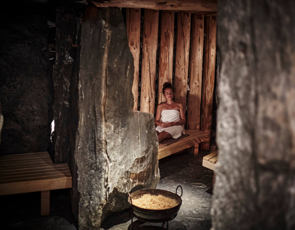 Frau entspannt in Sauna mit Naturstein und Holz im Luxushotel Salzburger Land Spa