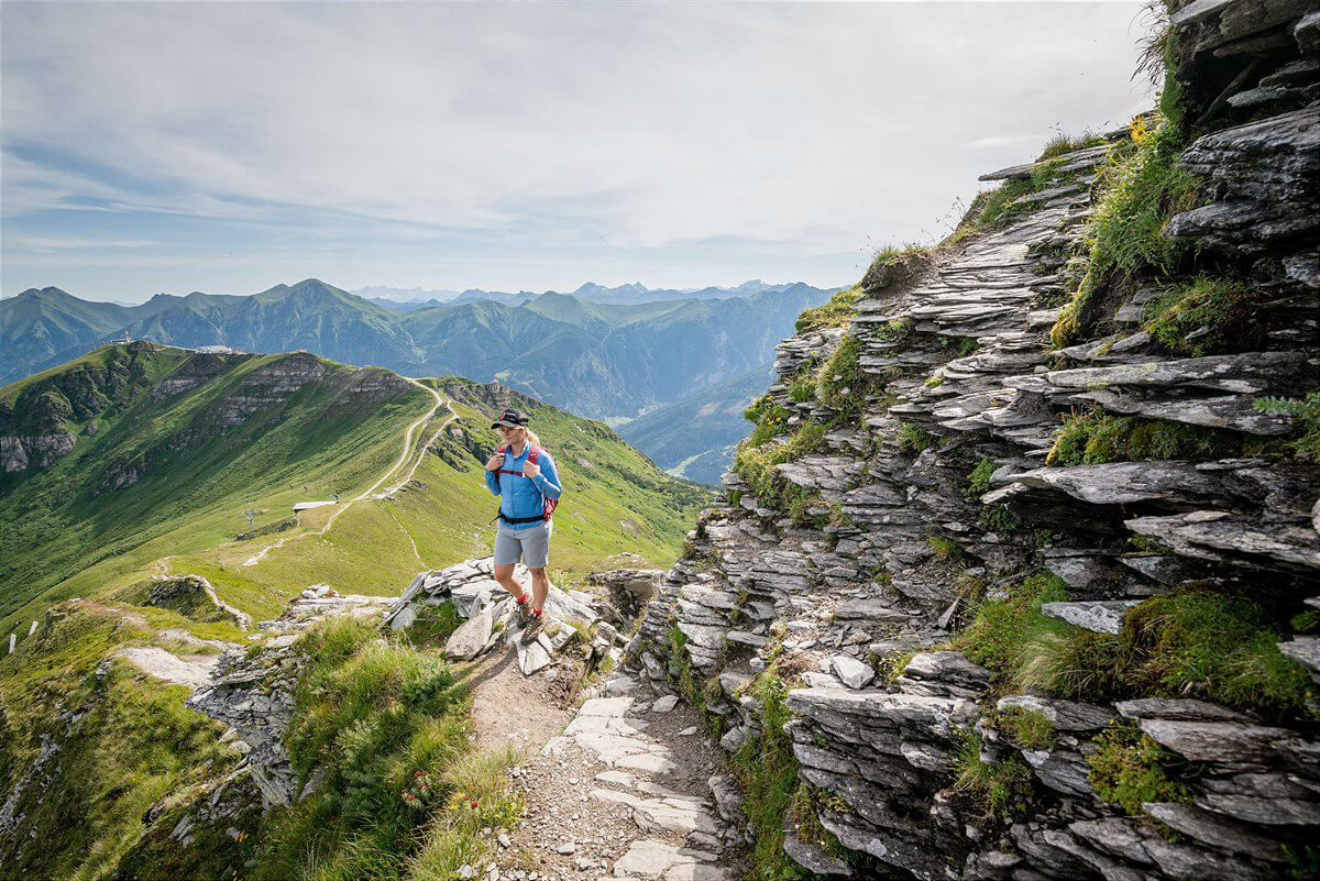 Wanderer auf Bergpfad mit Alpenblick im Salzburger Land Naturhotel und Aktivurlaub