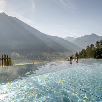 Zwei Personen im Infinity-Pool mit Bergpanorama im Wellnesshotel im Salzburger Land