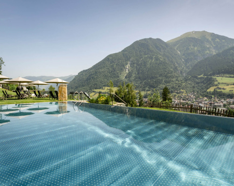 Infinity Pool mit Bergpanorama und Liegestühlen im Wellnesshotel Salzburger Land