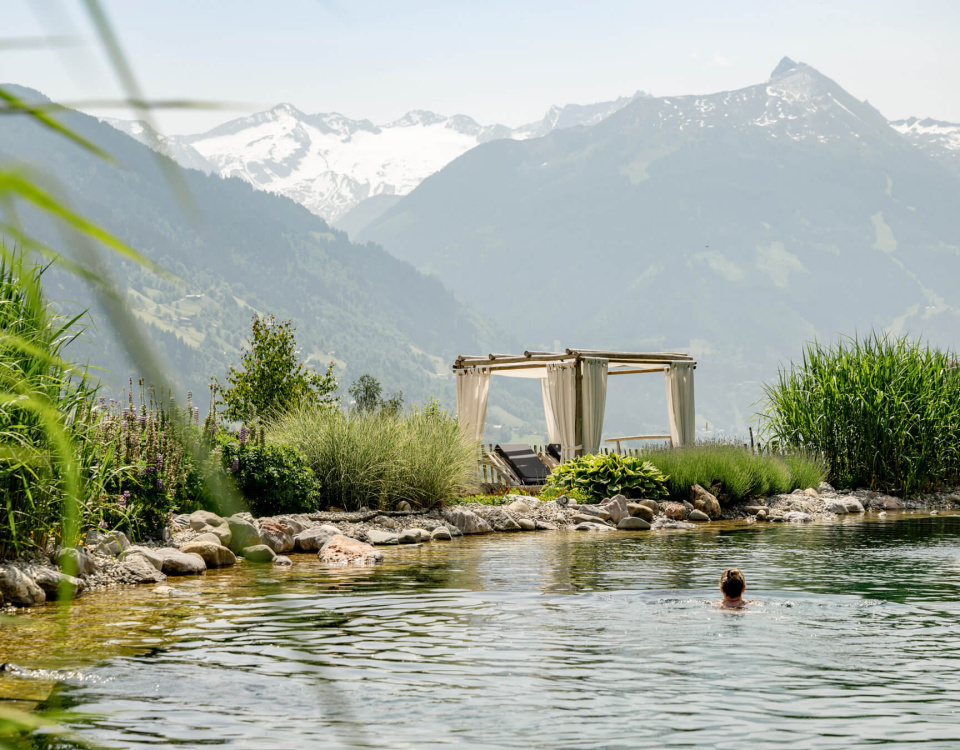 Person beim Schwimmen im Naturbad mit Bergpanorama im Wellnesshotel Salzburger Land