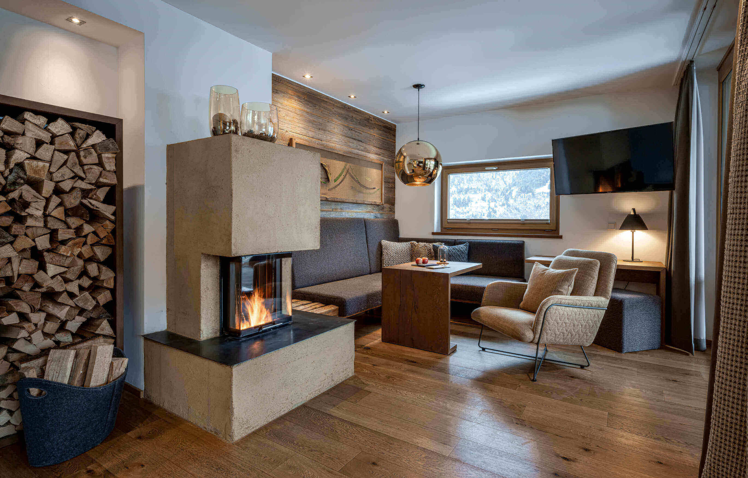 Gemütlicher Sitzbereich mit Kamin und Holzlager in Designhotel im Salzburger Land