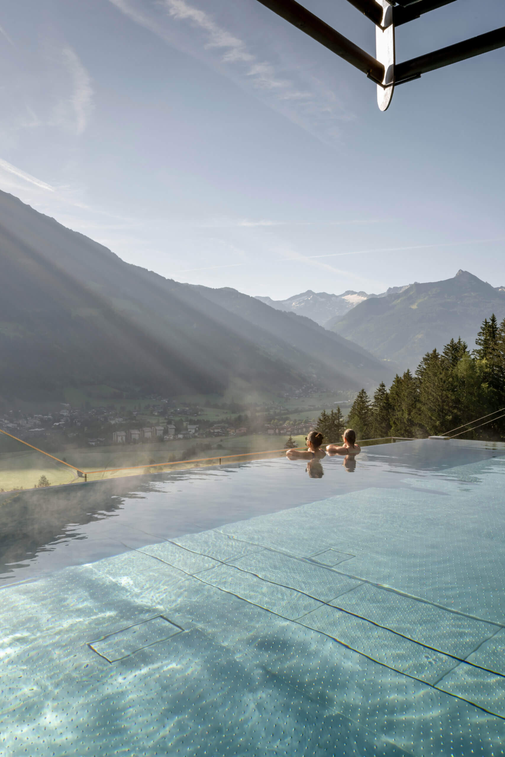 Zwei Personen entspannen im Infinity-Pool mit Bergpanorama im Designhotel DAS.GOLDBERG