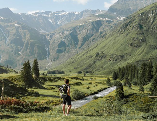 Wanderer blickt auf Bergtal mit Fluss in den Alpen bei Bad Hofgastein Naturhotel Urlaub