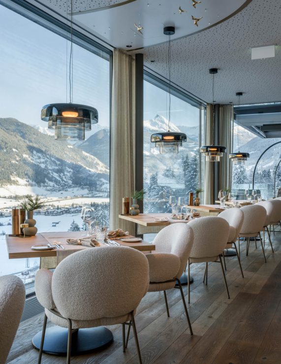 modernes Restaurant mit Panoramafenstern und Blick auf verschneite Berge im Wellnesshotel Bad Hofgastein