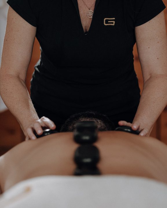 Hot-Stone-Massage auf Rücken eines Gastes