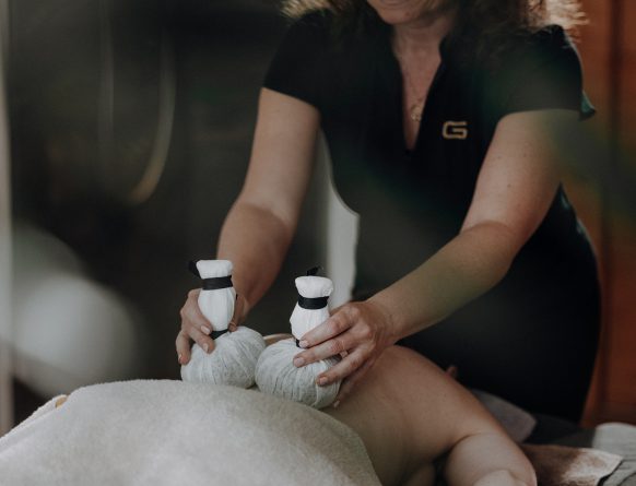 Wellnessbehandlung mit Kräuterstempeln auf dem Rücken