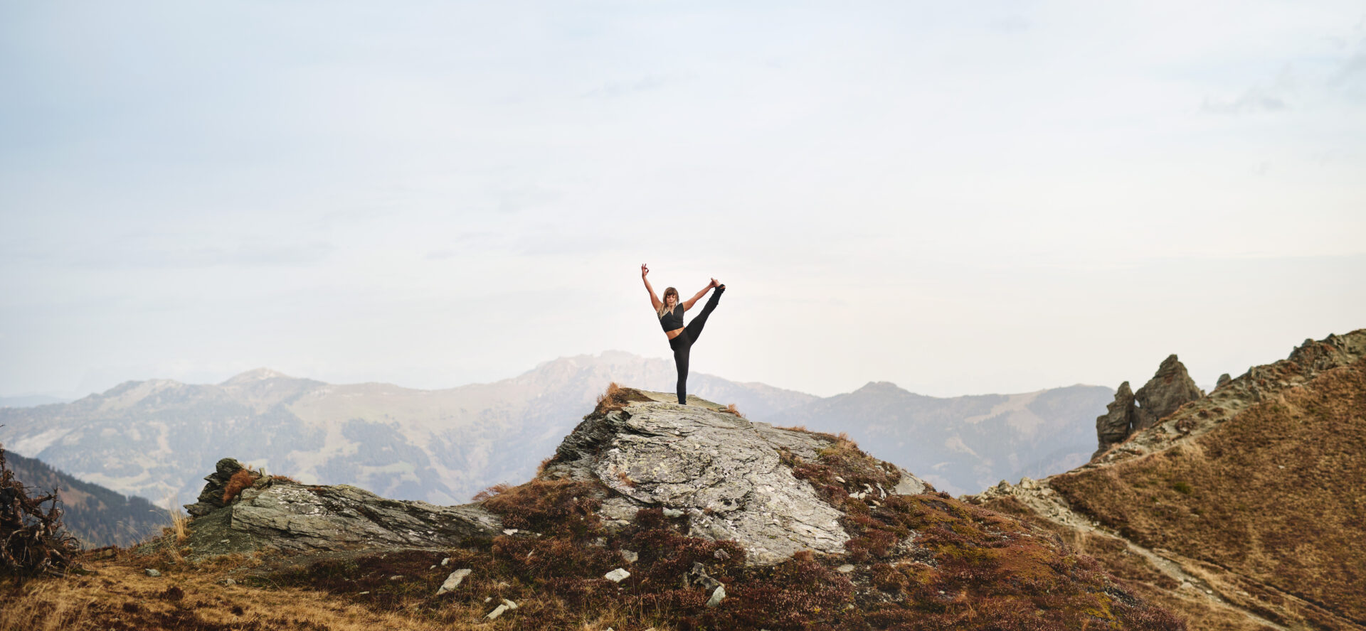 Person macht Yoga-Pose auf Felsen in den Bergen