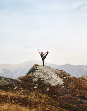 Person macht Yoga-Pose auf Felsen in den Bergen