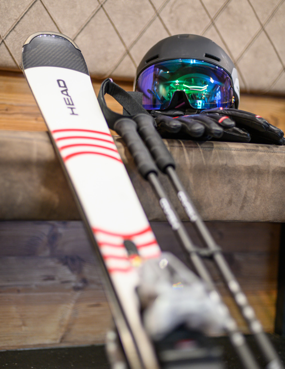Ski, Stöcke, Helm und Handschuhe auf einer gepolsterten Bank abgelegt