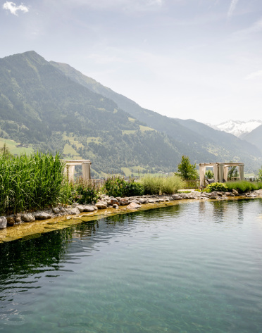 Naturbadesee mit Schilf, Liegen und Bergpanorama im sommerlichen Gasteinertal