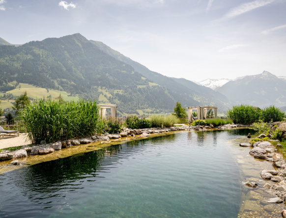 Naturbadesee mit Schilf, Liegen und Bergpanorama im sommerlichen Gasteinertal