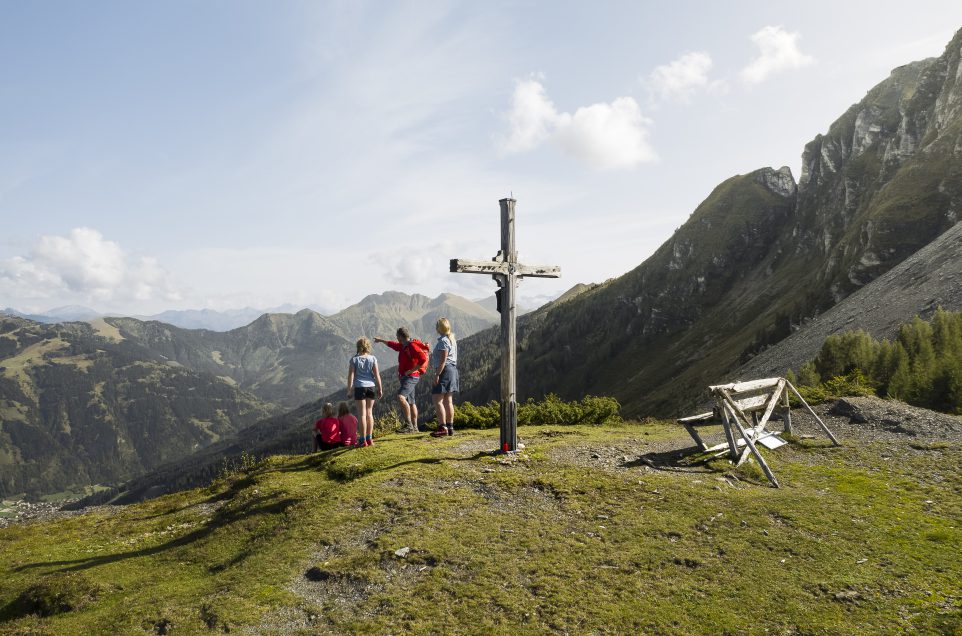 Familie am Gipfelkreuz mit Blick auf Berge im Gasteinertal