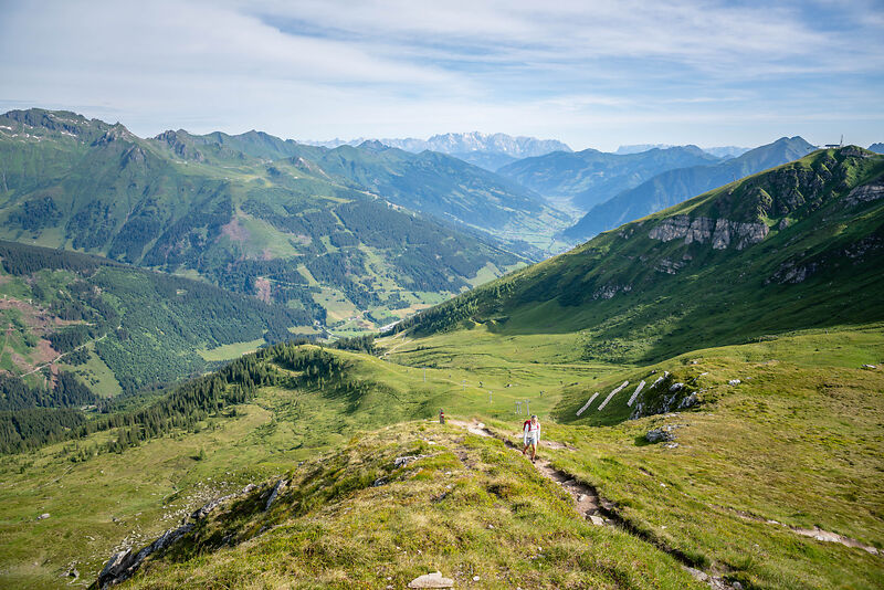 Wanderer auf grünem Bergpfad mit Blick ins Gasteinertal und Alpenpanorama