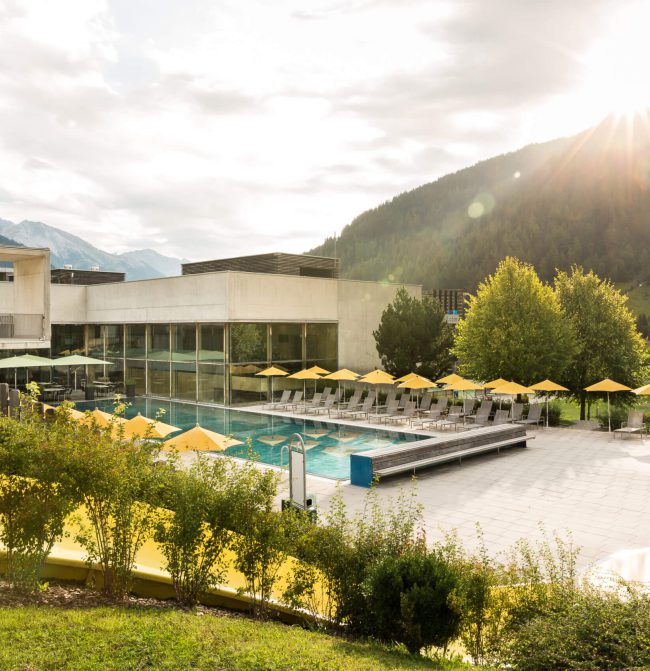 Wellnessbereich mit Pool und Liegestühlen, umgeben von Bergen und Natur in Flirsch, Tirol.