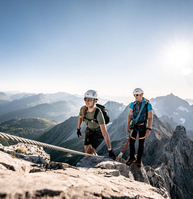 Kletterer auf dem Gipfel der Alpen mit Aussicht auf die umliegenden Berge.