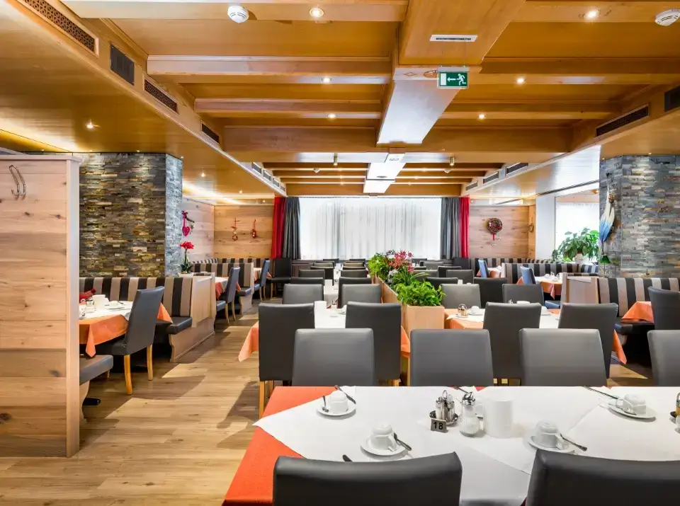 Gemütlicher Speisesaal im Hotel Grissemann mit Tischen und Pflanzen im Alpenstil.