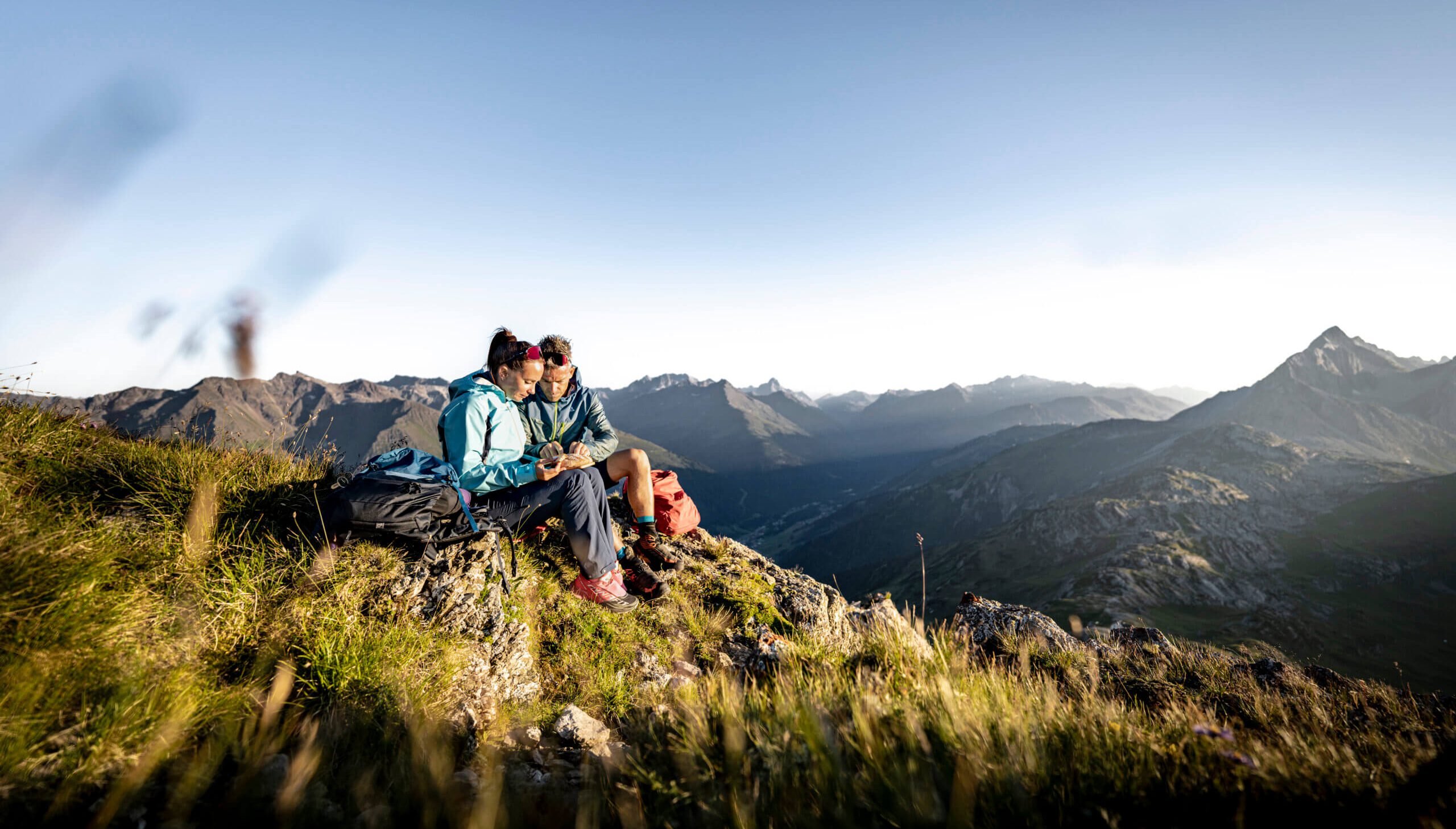 Paar sitzt auf einem Berg und genießt die Aussicht in den Alpen bei Flirsch am Arlberg.