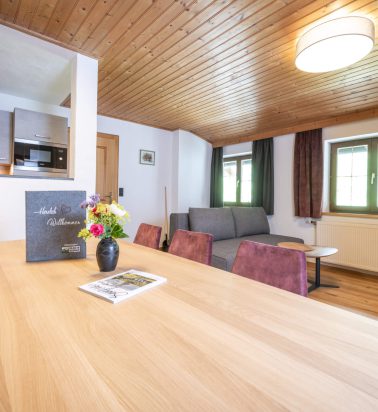 Moderne Ferienwohnung mit Holzdecke, gemütlichem Essbereich und Blick aus dem Fenster.