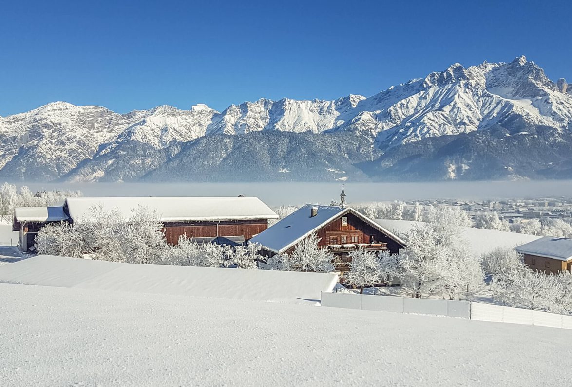 Schneebedeckte Berglandschaft mit dem Hinterburghof und modernen Appartements in Saalfelden.
