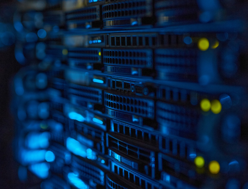 Rack server con illuminazione blu e spie di stato gialle in una sala tecnica buia