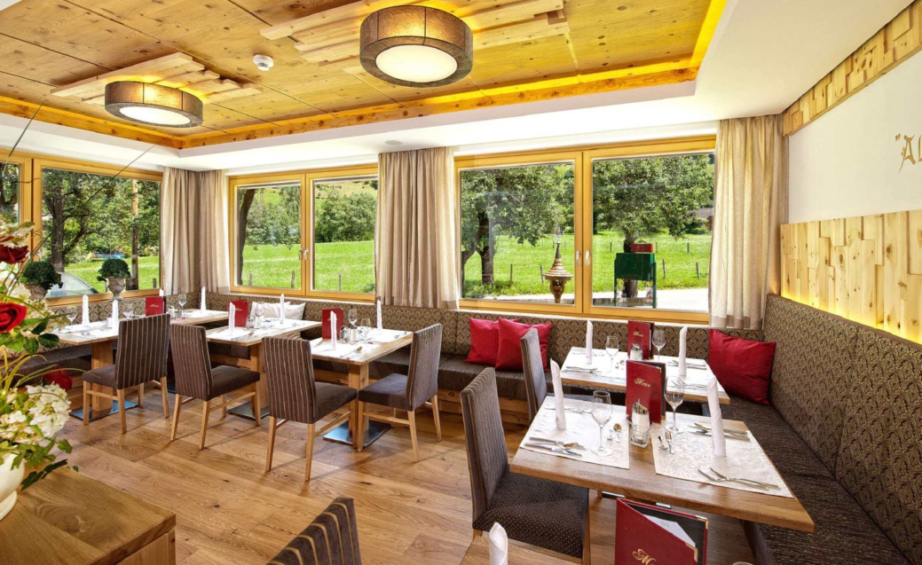 Heller Hotel-Speisesaal mit gedeckten Tischen, gepolsterten Stühlen und Blick auf eine grüne Wiese