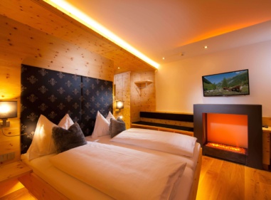 Gemütliches Hotelzimmer mit zwei Einzelbetten, Holzvertäfelung, Elektrokamin und Wandfernseher