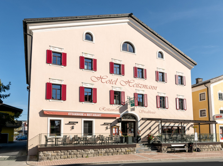 Fassade des Hotel Heitzmann mit Terrasse und roten Fensterläden