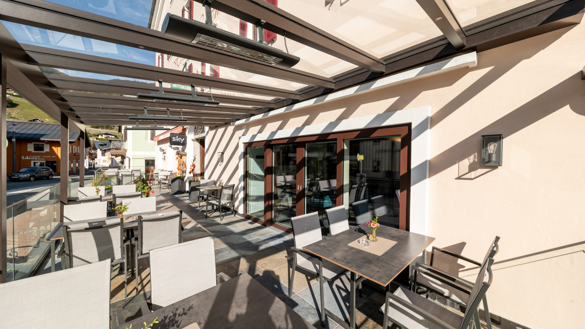 Überdachte Terrasse mit modernen Tischen und Stühlen im Hotel Mittersill