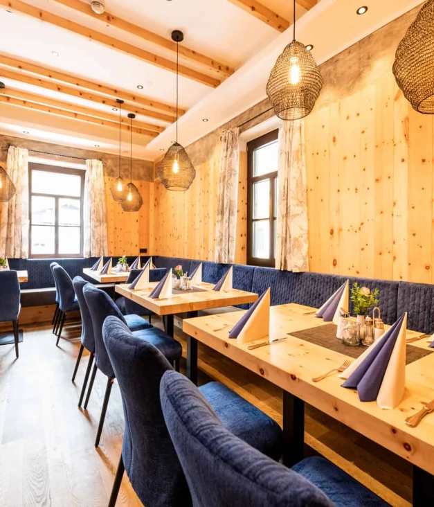 Modernes Restaurant mit Holzwänden, blauen Polsterstühlen und gedeckten Tischen
