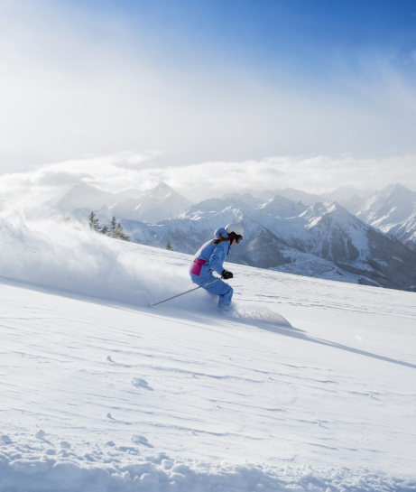 Skifahrerin auf verschneiter Piste vor Alpenpanorama