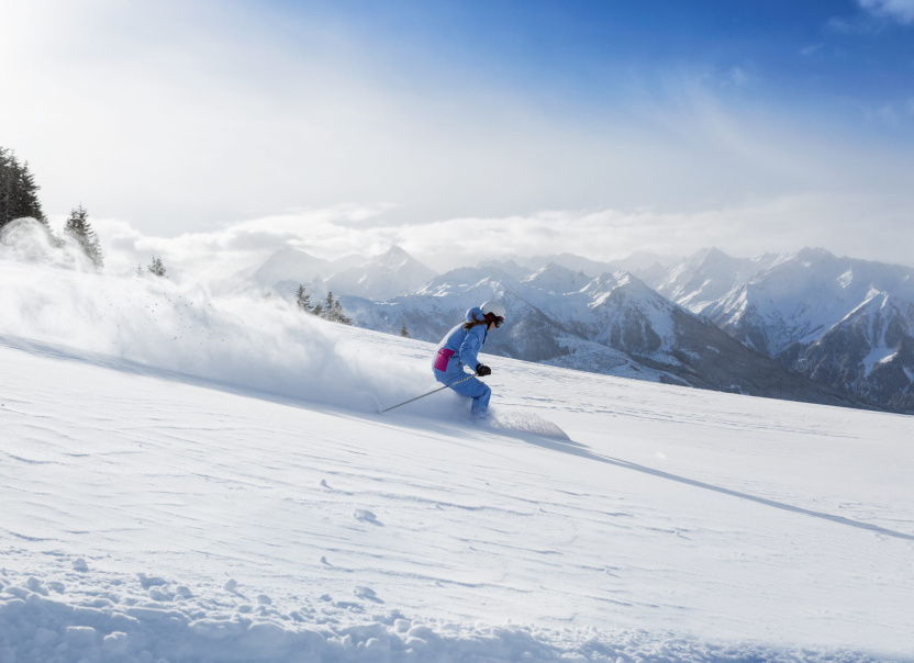 Skifahrerin auf verschneiter Piste vor Alpenpanorama