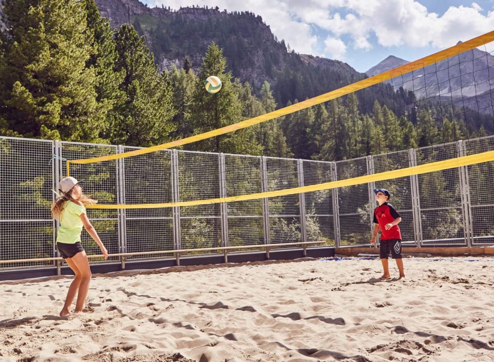 Zwei Kinder spielen Beachvolleyball auf Sandplatz am Jugendhotel Tauernhof Obertauern