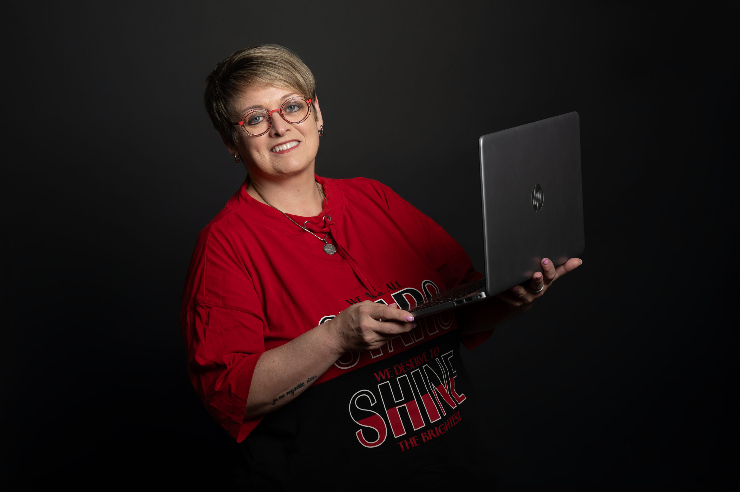 Frau mit rotem Shirt und Laptop vor schwarzem Hintergrund Autorin Liebesromane