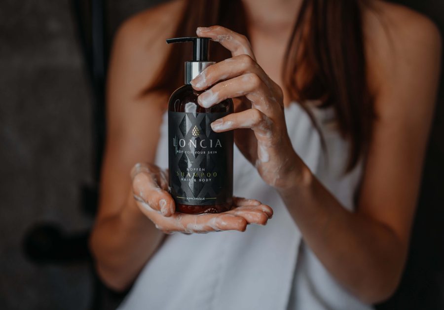 Frau mit Handtuch hält LONCIA Shampoo, natürliche hopfenkosmetik, sanfte hautpflege