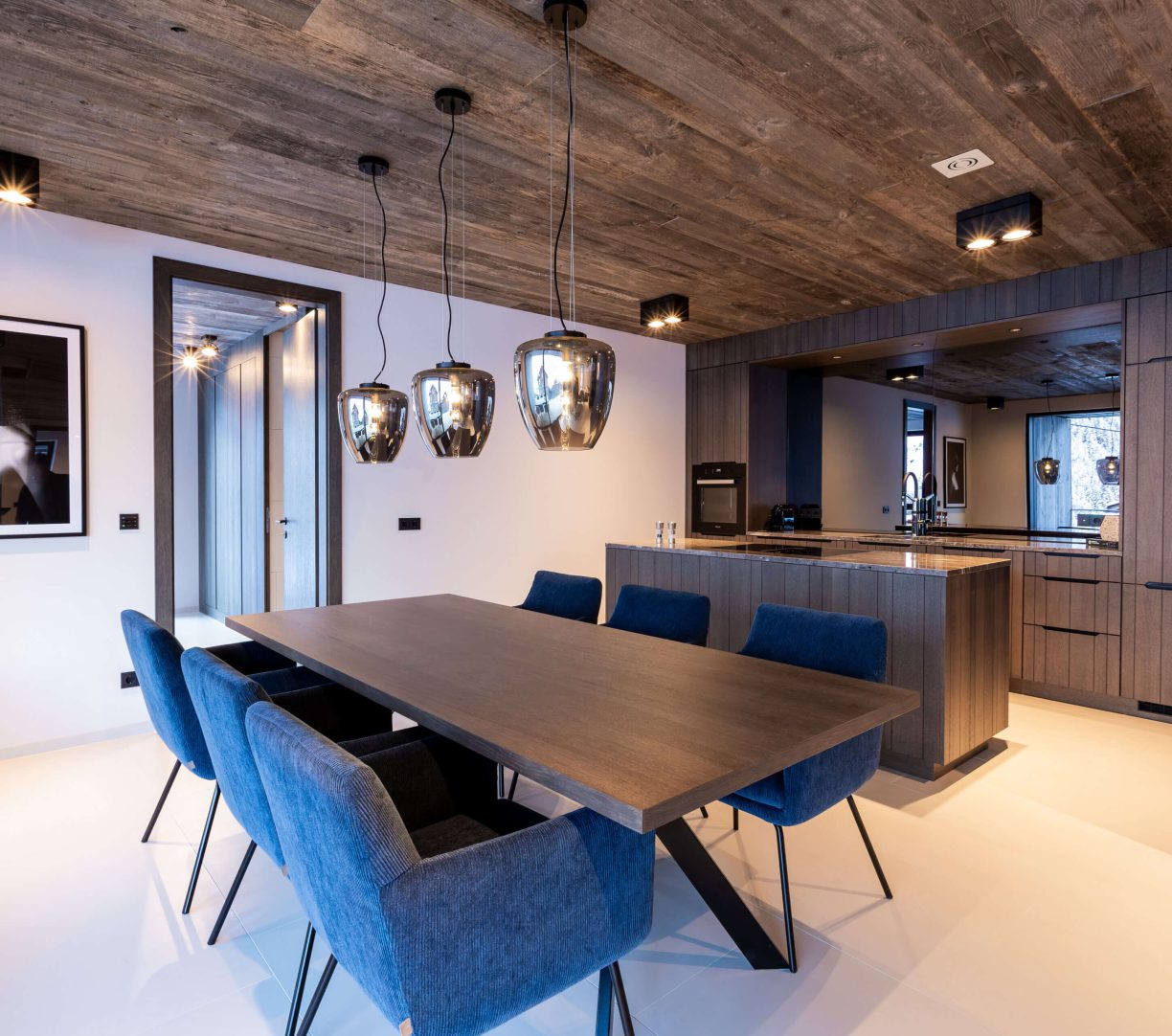 Moderner Essbereich mit blauen Stühlen und offenen Küche im Mountain Chalet Kappl.
