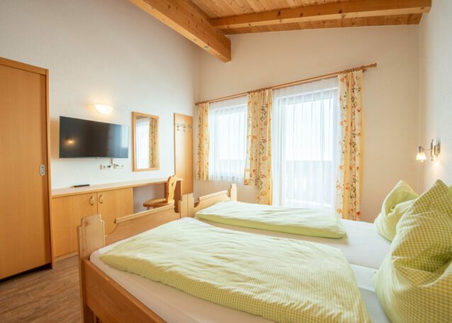 Helles Alpenzimmer mit Doppelbett Holzmöbeln Balkonblick und TV im Hohen Tauern